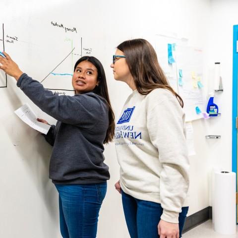 Students conduct cost-benefit analysis on a whiteboard